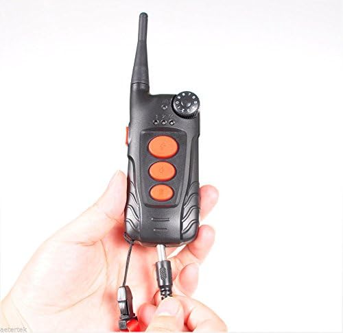 Hand holding the Aetertek AT-918C remote transmitter, showing the charging port.