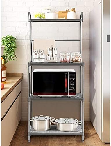 A grey 4-tier microwave oven rack in a kitchen setting, holding a microwave on the second shelf, spices and fruit on the third, and pots on the bottom shelf.