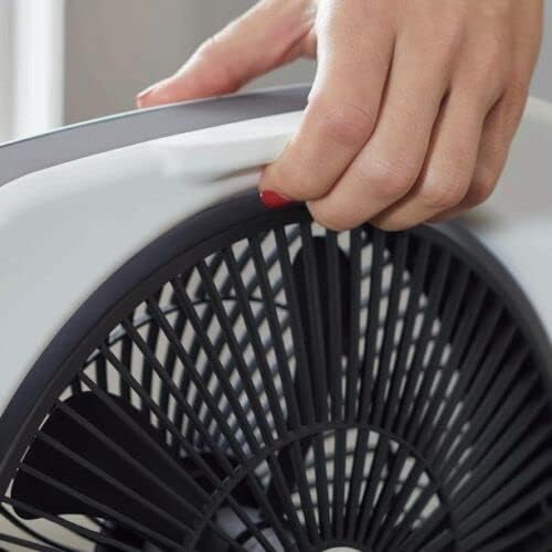 A hand holding the integrated handle of the portable fan.