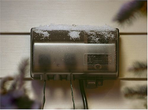 Hubbell FB3003 power strip with its weatherproof cover closed, lightly covered in snow, demonstrating its outdoor durability.