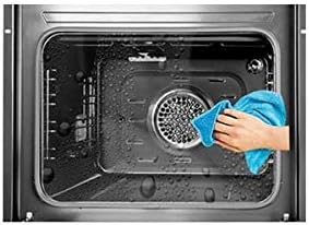 Hand cleaning the interior of an oven with a blue cloth