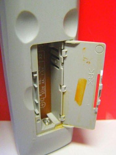 Open battery compartment of the ONKYO RC-506M remote control with battery polarity indicators