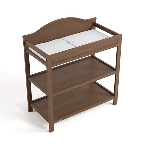 Image of Graco Story Changing Table with Water-Resistant Pad - GREENGUARD Gold Certified Baby Changing Station with Safety Strap, 2 Open Shelves, and a Nursery Must-Have Design (Hazelnut)