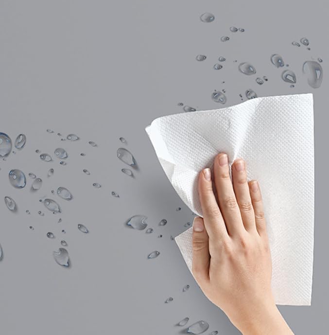 Hand wiping a surface with a white cloth, with water droplets visible, indicating cleaning.