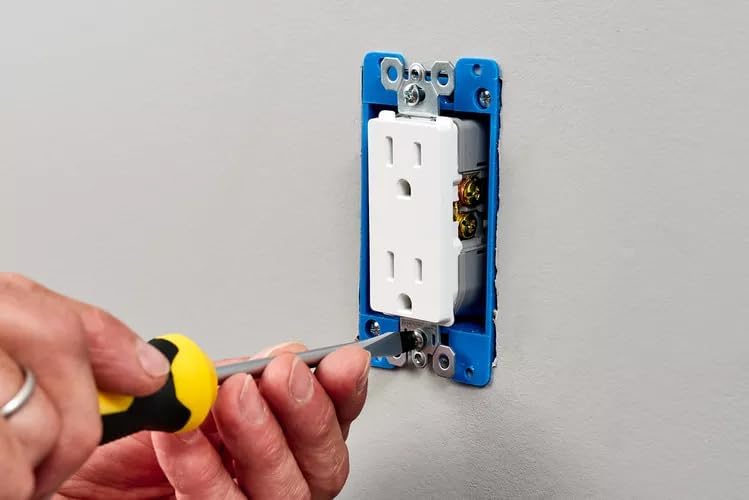 A person using a screwdriver to secure the AES Spy Cameras wall outlet camera into an electrical wall box.