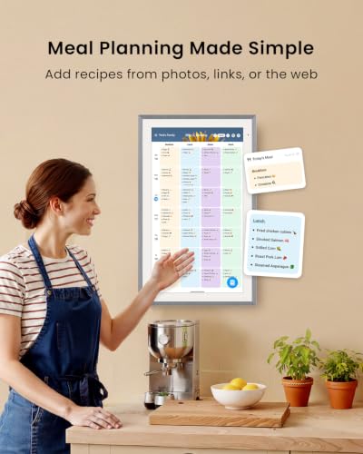 Woman in a kitchen beside a wall-mounted digital family planner displaying meal plans, recipes, schedules, and shopping notes.