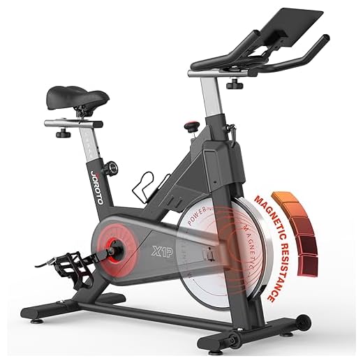 JOROTO Bicicleta Estática Magnética, bici estatica para en Casa con transmisión por correa, manillar ajustable en 4 direcciones, monitor LCD, soporte para tableta extra grande, capacidad de 150 kg.
