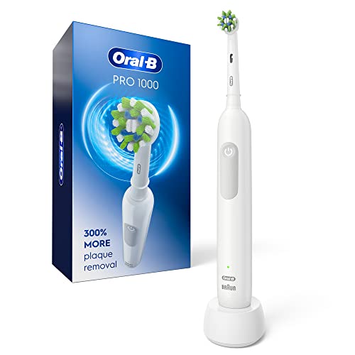 Oral-B Pro 1000 Rechargeable Electric Toothbrush in classic White finish standing on its charging puck on a bathroom counter, the round oscillating-rotating brush head with CrossAction angled bristles visible at the top, the simple single-button design on the handle, the Oral-B logo etched at the front of the handle — the most-recommended electric toothbrush for first-time buyers per Wirecutter and Consumer Reports, with the deepest Amazon review depth on this list at 61,743 reviews