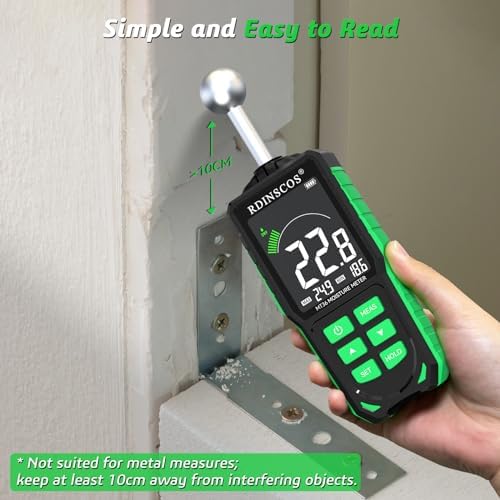 Hand holding the moisture meter against a wall for measurement.