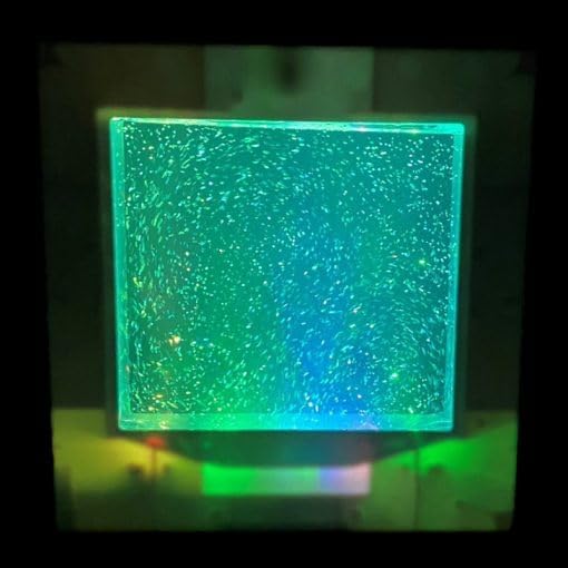 Close-up of the Playlearn Sensory Light displaying a vibrant green color with glitter movement