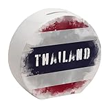Auf der Spardose ist die thailändische Flagge im used look zu sehen. In der Mitte befindet sich der Ländername. Die Dose ist rund mit einer flachen Kante, auf der sie sicher abgestellt werden kann. Die Grundfarbe der Dose ist Weiß.