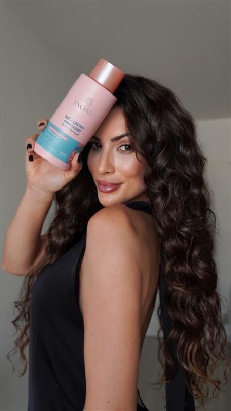 Mulher com cabelos cacheados segurando um frasco rosa de shampoo Inoar Meu Cacho Meu Crush