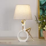 Design artistique : lampe de table élégante avec une figurine décorative perchée sur une base circulaire, finition en blanc et or pour un attrait esthétique moderne
