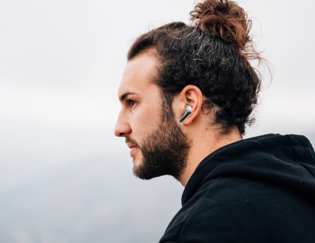A person wearing one Misik MH612-B earbud, demonstrating its in-ear fit.