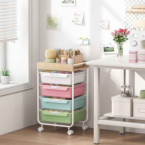 Rolling craft cart with four pastel-colored drawers and a wooden top holding yarn beside a white desk in a bright craft room.