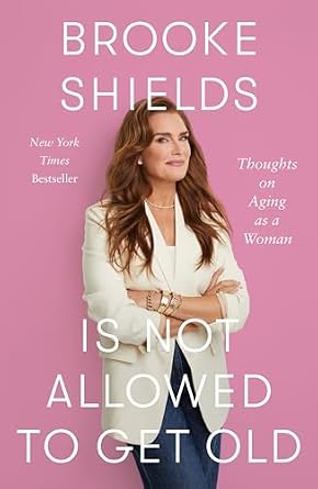 Brooke Shields Is Not Allowed to Get Old: Thoughts on Aging as a Woman by Brooke Shields and Rachel Bertsche a memoir book cover depicting the model Brooke Shields in a whit blazer and jeans leaning against a pink wall.