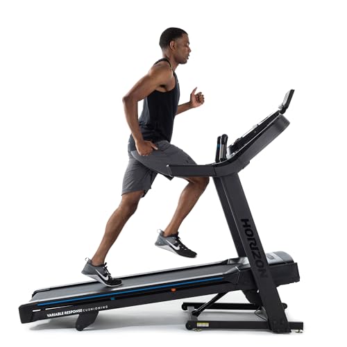 Side profile view of a muscular Black man in a black tank top and gray shorts running dynamically on the black Horizon Fitness 7.0 AT folding treadmill, mid-stride with one leg extended forward and arms pumping, wearing black Nike running shoes; the 20" x 60" running belt features blue accent lines and orange markers, labeled "VARIABLE RESPONSE CUSHIONING" along the deck edge, with the sturdy black frame, blue-handled QuickDial controls, angled console, and "HORIZON" branding visible on the side and uprights, shown against a clean white studio background.