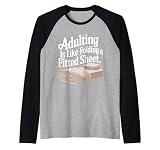 Adultar es como doblar una sábana Camiseta Manga Raglan