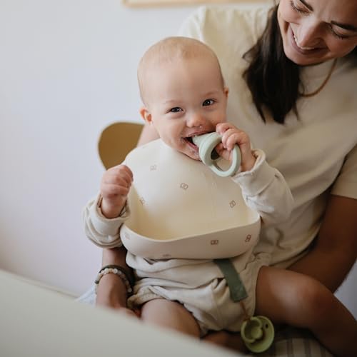 Image of mushie Silicone Baby Bib | Adjustable Fit Waterproof Bibs (Pretzel)