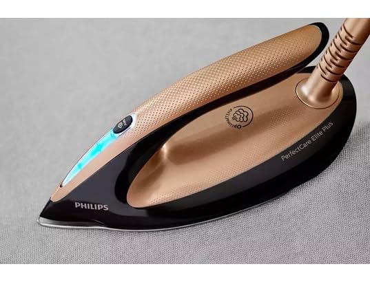 Centrale vapeur Philips noire et cuivre posée sur le support latéral d'une table à repasser.