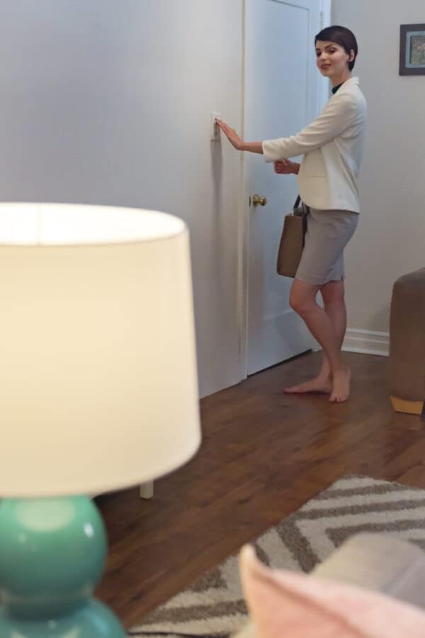 Person operating a wall light switch to control a Feit Electric Intellibulb