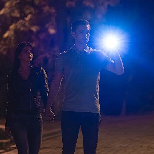 Person camping under a starry sky, illuminating the tent and surroundings with a flashlight