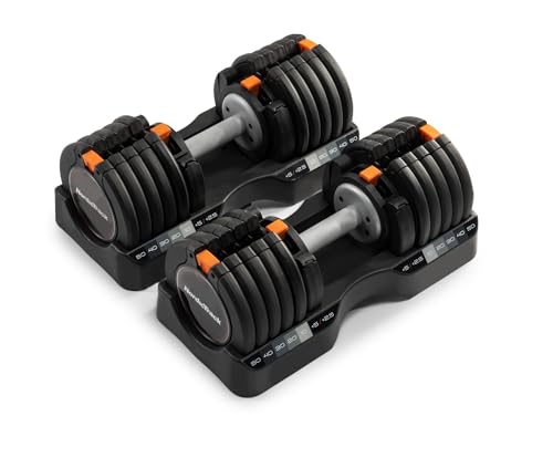 NordicTrack Select-a-Weight adjustable dumbbells in dark gray and black on a wood-frame storage tray, the long-form handle clearly longer than the PowerBlock cube design, the dial-selector mechanism visible at the end of each handle with weight increment markings, the steel plate stack extending the full length of the handle, the included custom-molded storage trays positioned underneath the dumbbells holding the unused plates -- the long-handle selectorized alternative to the PowerBlock cube for lifters who prefer a traditional dumbbell feel and the right cross-shop for buyers who want included storage trays without buying a separate stand.