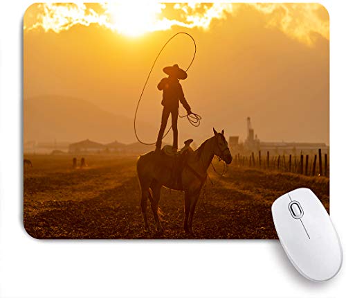 Mauspad,Ein junger mexikanischer Charro sammelt eine Herde Pferde, die bei Sonnenaufgang auf einer mexikanischen Ranch durch ein Feld