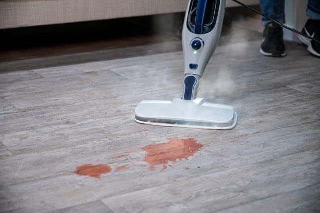 Steam mop cleaning a spill on a hard floor