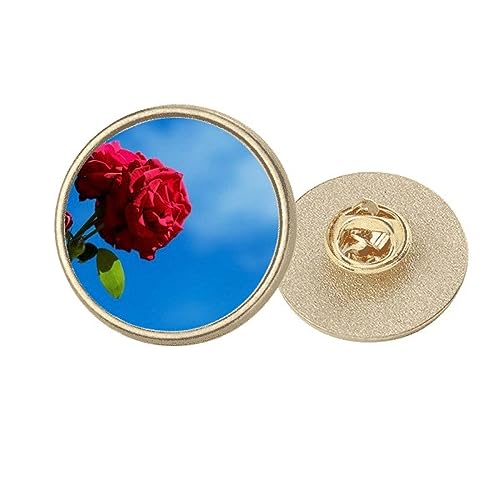 Broche ronde en métal doré ornée de roses rouges sur fond bleu ciel