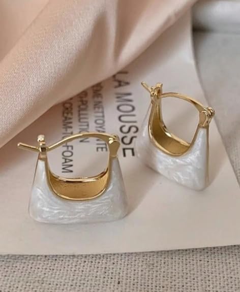 Pair of white and gold square hoop earrings resting on a light-colored fabric, showing the clasp mechanism.