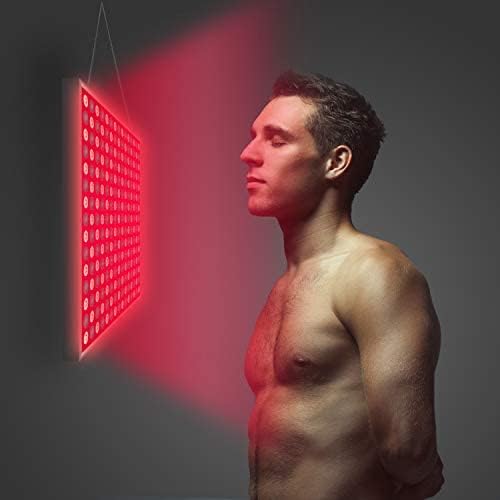 Man using the red light therapy panel on his face