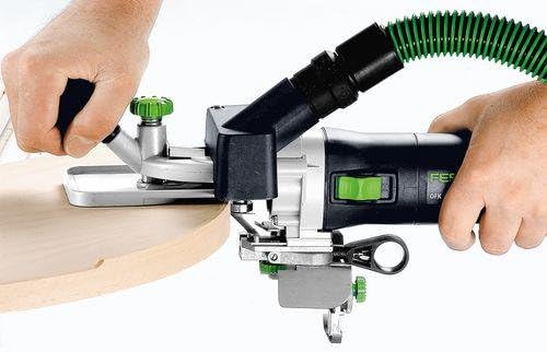 User operating the Festool OFK 700 EQ-Plus on a curved wooden edge, demonstrating edge milling