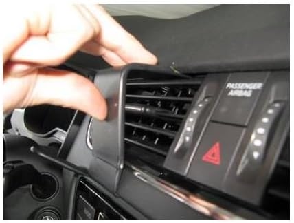 A hand inserting the lower edge of the Brodit ProClip into the dashboard gap above the central display and air vents.