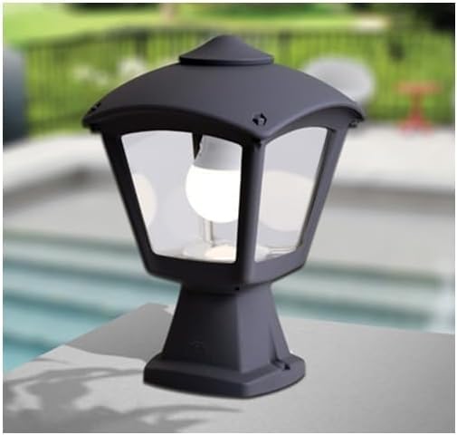 Фумагалли бакчасы Lamp installed on a low wall in an outdoor garden setting, with blurred greenery and a pool in the background.