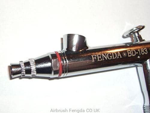 Close-up view of the Fengda BD-183 airbrush body, showing the nozzle cap, trigger, and paint cup connection.