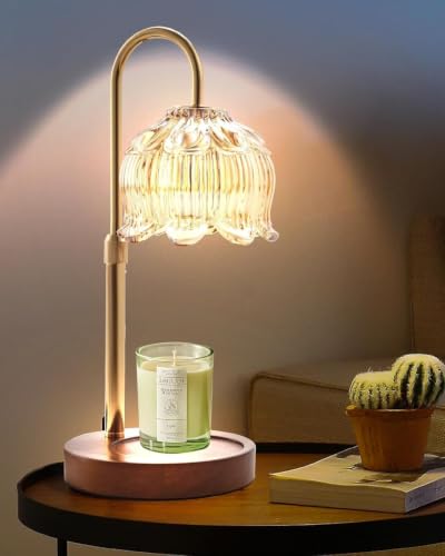 Tall gold and wood warmer lamp lit above a jar candle — showing the statement-lamp scale in a room setting