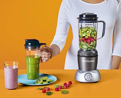 A person holding a Nutribullet travel cup with a green smoothie, next to the Nutribullet Select Blender with a pitcher full of fruits and vegetables.