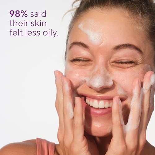 Woman massaging foaming cleanser across her cheeks and forehead
