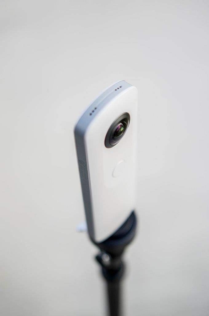Ricoh Theta SC camera mounted on a tripod, capturing a scene.