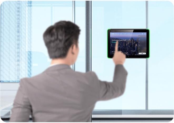 A person interacting with a Yealink RoomPanel mounted on a glass wall, pointing at the screen.