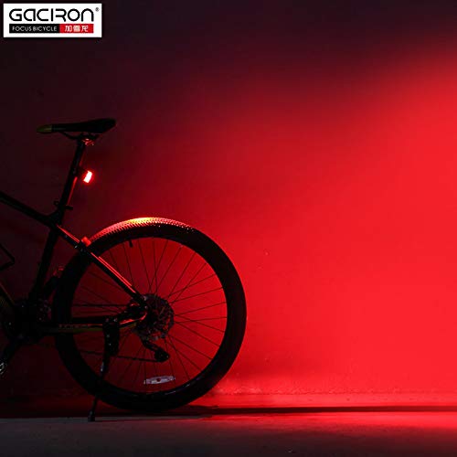 Bicycle with Saddle Up Gaciron W09 tail light illuminated in a dark environment, casting a bright red glow