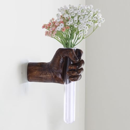 A sculptural hand mounted on the wall holding a tiny test tube vase — part art piece, part flower holder, total conversation starter.