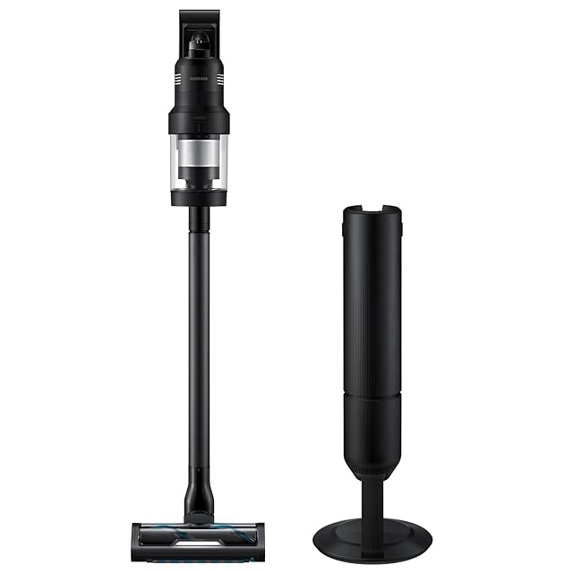Samsung Bespoke AI Jet Ultra cordless stick vacuum in white with the matte navy Bespoke trim, mounted in the All-in-One Clean Station auto-empty base on the floor of a modern American home, the bagged collection chamber visible at the dock so the user never sees dust during emptying, the lightweight 5.5 lb wand assembly extending up from the dock, the dual-battery indicator on the body showing both packs at full charge — the only fully sealed bagged auto-empty option in this guide.