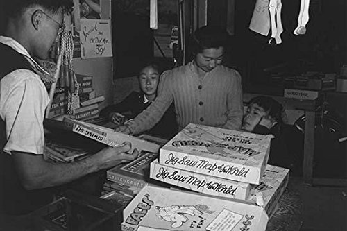 Mrs Yaeko Nakamura looks at puzzles with her daughters Louise Tami Nakamura and Joyce Yuki Nakamura in a store with assistance from clerk Ansel Easton Adams (1902 1984) was an American photographer