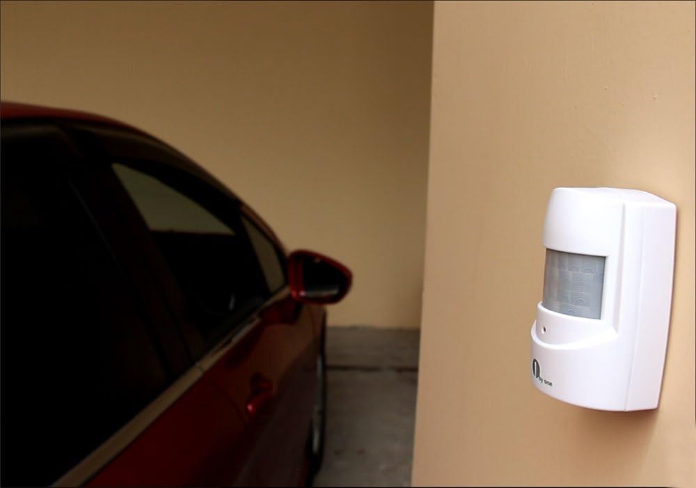 PIR sensor mounted on a wall next to a car in a garage or carport.