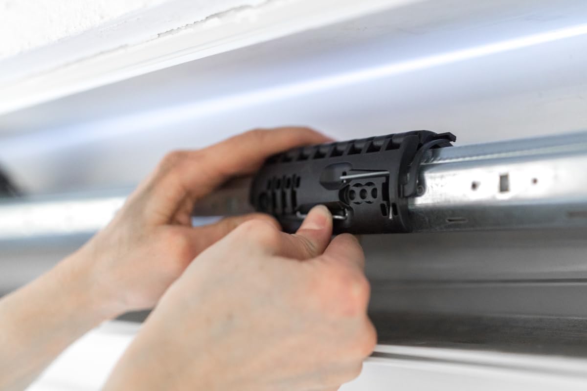 Hands attaching the Schellenberg anti-lift device to an octagonal roller shutter shaft.