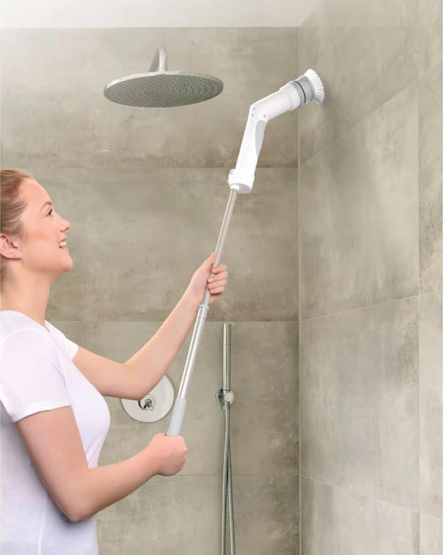 Person cleaning a shower wall with the Silvercrest cordless cleaning brush attached to its telescopic handle.