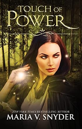 Touch of Power by Maria V. Snyder, a fiction book cover depicting a young woman in a green cloak with long dark hair, looking to the side, standing against a misty green forest backdrop, with a half raised glowing hand, and the title in light green at the top.