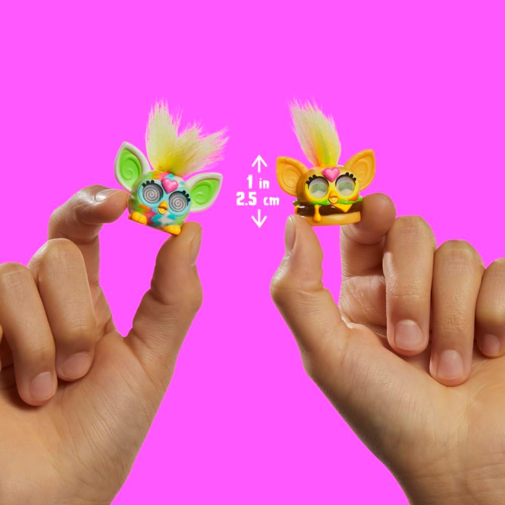 Two hands holding two Furby Fur MINIS, illustrating their small size.